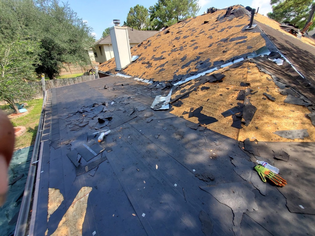 Roof during a full tear-off, with old shingles removed down to the deck