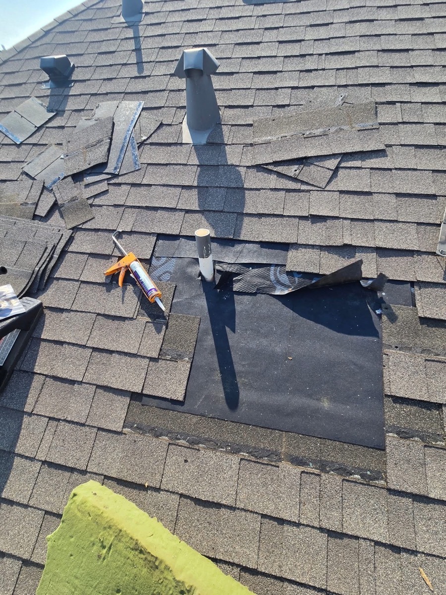 Close-up of roof repair work in progress, showing exposed underlayment and sealant